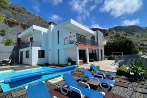 a villa with a swimming pool and blue chairs at Villa Nunes, Big Holiday house with private pool in Calheta