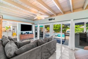 a living room with a couch and a tv at Seaside Elegance - 4B-4B - 3 Master Suites, Heated Pool and Spa, Tanning Ledge, Golden Tee Arcade, Outdoor Bar with 65 Inch TV, BBQ, Walk to Beach! Sleeps 10 in West Palm Beach