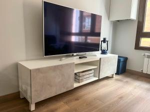 un centro de entretenimiento blanco con una gran televisión en la pared en Apartamento Barrio de la Arena, en Gijón