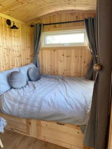 Cama en habitación de madera con ventana en Beautiful 1 Bed Shepherd Hut in Warwickshire, en Warwick