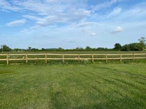 a wooden fence in a field next to a green field at Beautiful 1 Bed Shepherd Hut in Warwickshire in Warwick