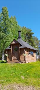a log cabin with a black roof on a green field at Huoneisto Riekko in Suomussalmi