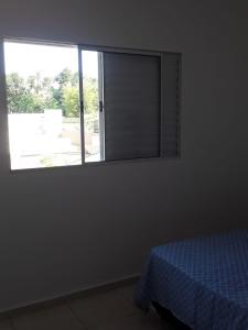 a bedroom with a window with a blue bed in it at casa de praia campos in Itanhaém