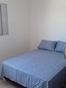 a bed in a bedroom with a blue comforter at casa de praia campos in Itanhaém