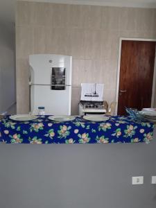a kitchen with a refrigerator and a table with plates at casa de praia campos in Itanhaém