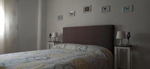 1 dormitorio con 1 cama y 2 lámparas y cuadros en la pared en Piso Turístico Huétor Vega (Granada) en Huétor Vega