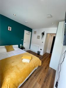 a bedroom with a bed with a yellow blanket at Beautiful Studio flat in Purley