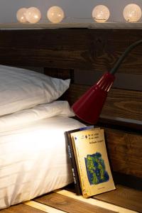 um livro e um candeeiro vermelho ao lado de uma cama em Casa Boemia em Braşov