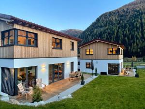 a large house with a deck with a yard at TYROL PURElife Lodges in Sankt Jakob in Defereggen