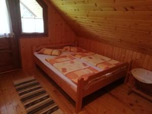a bedroom with a bed in a log cabin at Demény vendégház in Sub Cetate