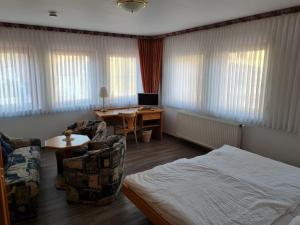 a bedroom with a bed and a desk with a computer at Pension Jung, Bäckerei-Konditorei & Café in Ruhla