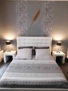 a bedroom with a large white bed with two tables at Ô Temps d'Amour Sauna&Jacuzzi in Malissard