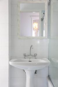 a white bathroom with a sink and a mirror at Villa Mavromichali private beach in Liaropá