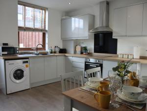 a kitchen with white cabinets and a table with dishes on it at Sheffield 3-bedroom house with free street parking in Sheffield