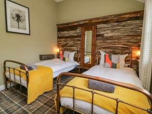 two beds in a room with a wooden wall at The Old Wagon Shed in Leven