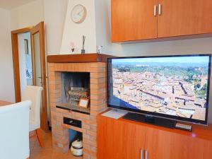 a television in a living room with a brick fireplace at [Siena] Appartamento con splendido terrazzo in Presciano