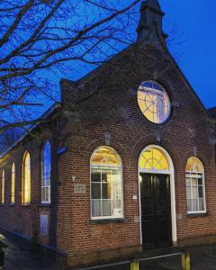 a brick church with windows and a door at Himelsk in Koudum