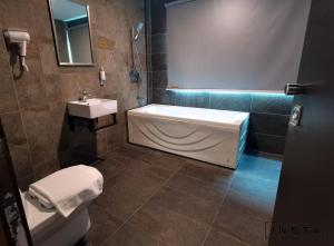 a bathroom with a tub and a toilet and a sink at Insta Hotel JB in Johor Bahru