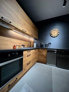 a kitchen with wooden cabinets and a clock on the wall at Prestige 12 in Zator