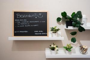 un cartello con la lavagna su un muro con piante in vaso di Loft in Centro con Camino - Sestola a Sestola