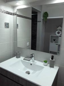 a white bathroom with a sink and a mirror at La Perle du Rocher in Le Diamant +38 photos