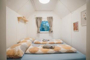 2 Betten in einem kleinen Zimmer mit Fenster in der Unterkunft Maringotka Olívie v Ivančicích in Ivančice
