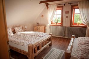 a bedroom with a large bed and two windows at Chalupa U Ceďora in Petrovičky