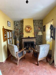 een woonkamer met 2 stoelen en een open haard bij Mirador del farmacéutico in Zahara de la Sierra
