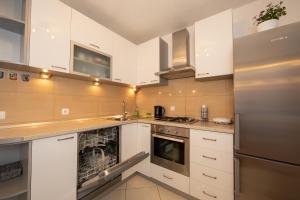 a kitchen with white cabinets and a stainless steel refrigerator at Apartmani Nina & Mili in Igrane
