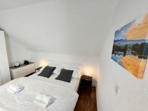 Apartments & rooms Velebit في Lovinac: غرفة نوم بسرير ذو شراشف بيضاء ومخدات سوداء