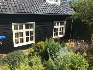 a black house with two windows and a garden at ’t Huuske in Zonnemaire