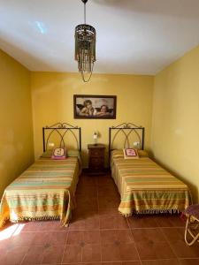 2 Betten in einem Zimmer mit gelben Wänden in der Unterkunft Mirador del farmacéutico in Zahara de la Sierra