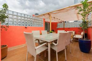 una mesa y sillas en un patio con una pared de color naranja en Stylish apartment with private roof top & jacuzzi, en Ciudad de México