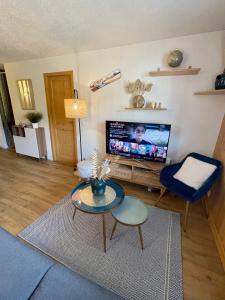 a living room with a tv and a blue chair at Au Petit Flocon - Appartement 3 pièces, central et proche pistes - parking privé et wifi in Megève +5 photos