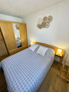 a bedroom with a bed with a blue comforter and a mirror at Au Petit Flocon - Appartement 3 pièces, central et proche pistes - parking privé et wifi in Megève