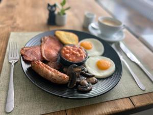 een bord ontbijtproducten met eieren, worst en bonen bij United Home B&B in Manchester