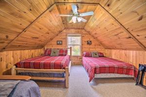 a log cabin bedroom with two beds and a ceiling fan at Lakefront Hawks Getaway - Fire Pit and Kayaks! in Hawks