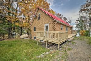 Cabaña de madera con porche y techo rojo en Lakefront Hawks Getaway - Fire Pit and Kayaks! en Hawks