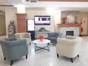 a waiting room with chairs and a table and a fireplace at Merit Hotel & Suites in Fort McMurray