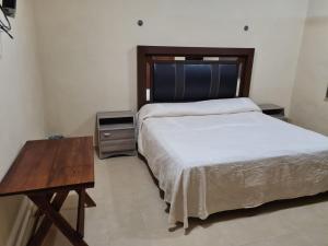 1 dormitorio con cama y mesa de madera en Hotel La Piramide Izamal, en Izamal