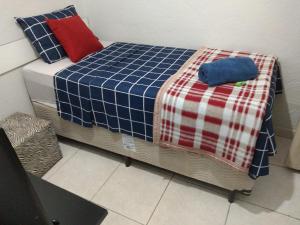 a bed with a blue and red plaid blanket on it at Recanto do Parque in Campo Grande