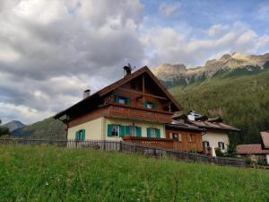 uma casa numa colina com montanhas ao fundo em Ciasa Rossi em Soraga