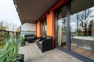 eine Terrasse mit einem Sofa und Stühlen auf dem Balkon in der Unterkunft Apartament Wyspa Solna Kołobrzeg in Kołobrzeg