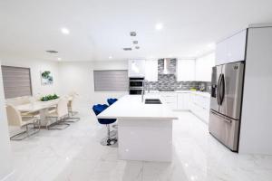 uma cozinha branca com frigorífico, mesas e cadeiras em Miami Family Home 5BR Heated Pool & Jacuzzi L45 em Tamiami