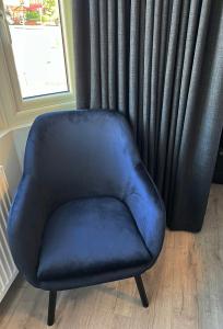 a blue chair sitting in front of a window at United Home B&B in Manchester