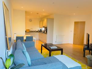 sala de estar con sofá azul y cocina en Spacious two Bedroom Apartment in Balham, en Londres