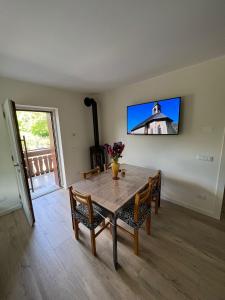 een eettafel met stoelen en een tv aan de muur bij Ca' Domani - Appartamento immerso nel Cadore in Domegge di Cadore