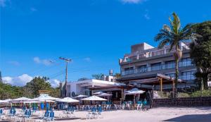 a hotel with chairs and umbrellas in front of a building at Hotel Village Enseada in Ubatuba