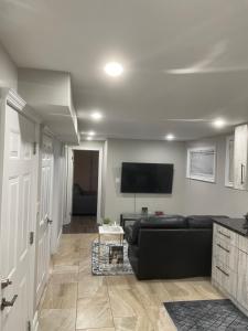 a living room with a black couch and a flat screen tv at Stunning & cozy freshly renovated 2 bedroom basement unit in Kitchener