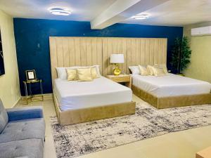 2 camas en una habitación con paredes azules y sofá en El Paso Hotel, 